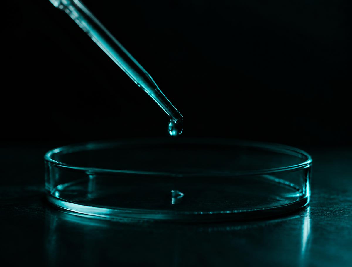 Pipette releasing a drop into a glass dish